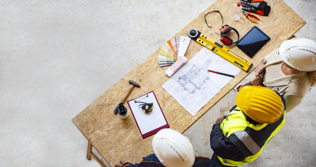 Custom homebuilders in hardhats studying home floor plan