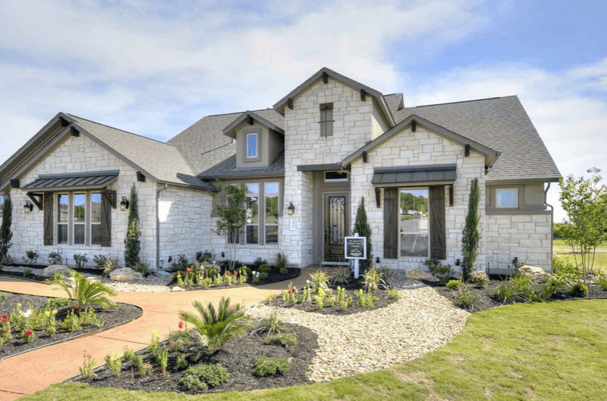 Custom home with natural white stone facade, grey roof, and a desert plant garden in the front yard