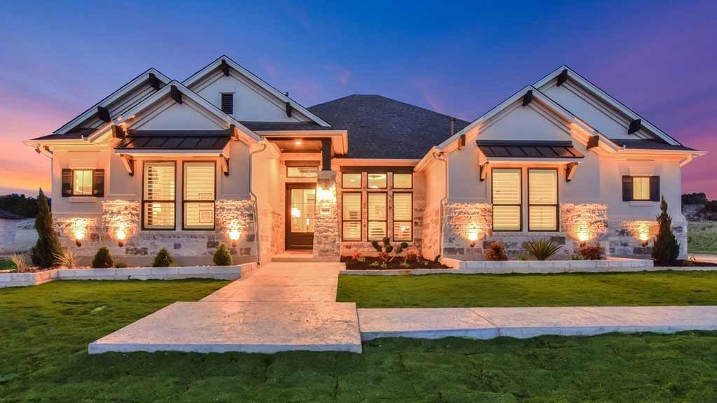 Modern custom home with natural stone facade against a purple sunset sky