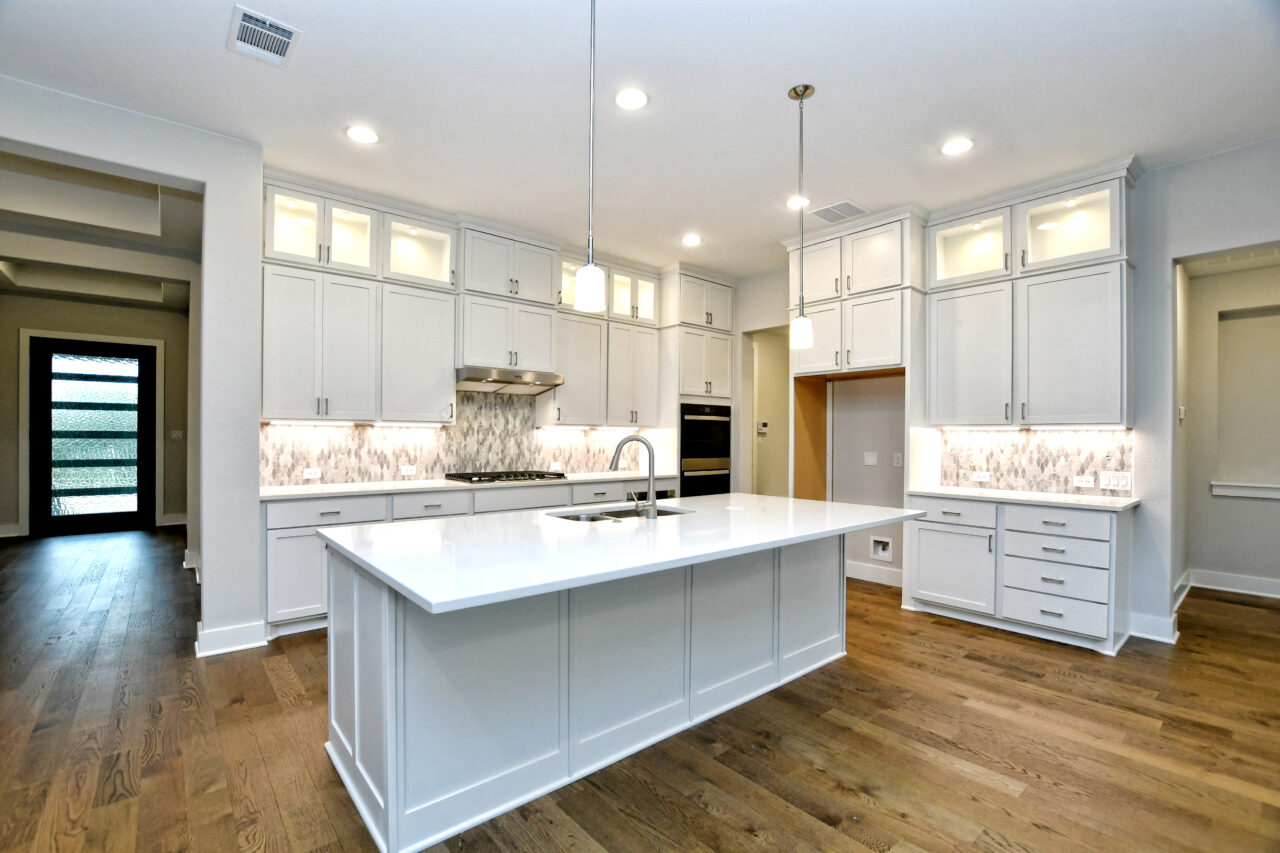 Kitchen, island with sink and white cabinets and granite. Hardwood floors.