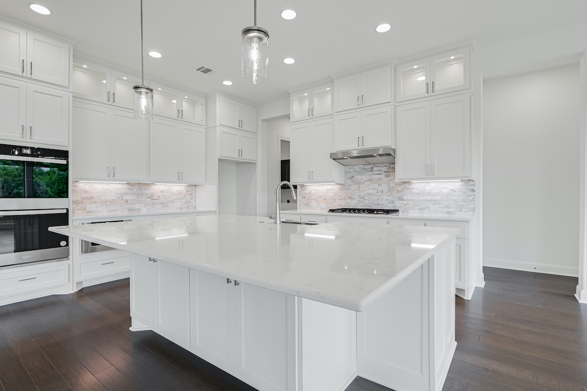 Interior kitchen of Ruby floor plan by Giddens Homes. Part of the Gemstone Series. Features large island and floor to ceiling cabinets. 