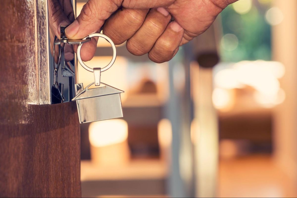 Stock image of someone unlocking the door to their home.
