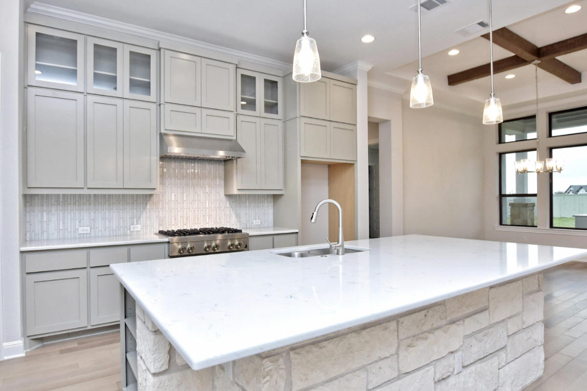 View of a Giddens Home kitchen with light gray cabinets and an island. 
